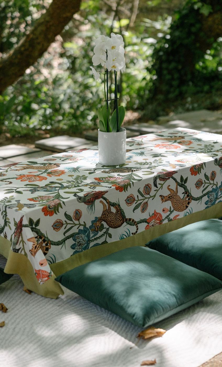 Table with a floral tablecloth, cushions and white flowers