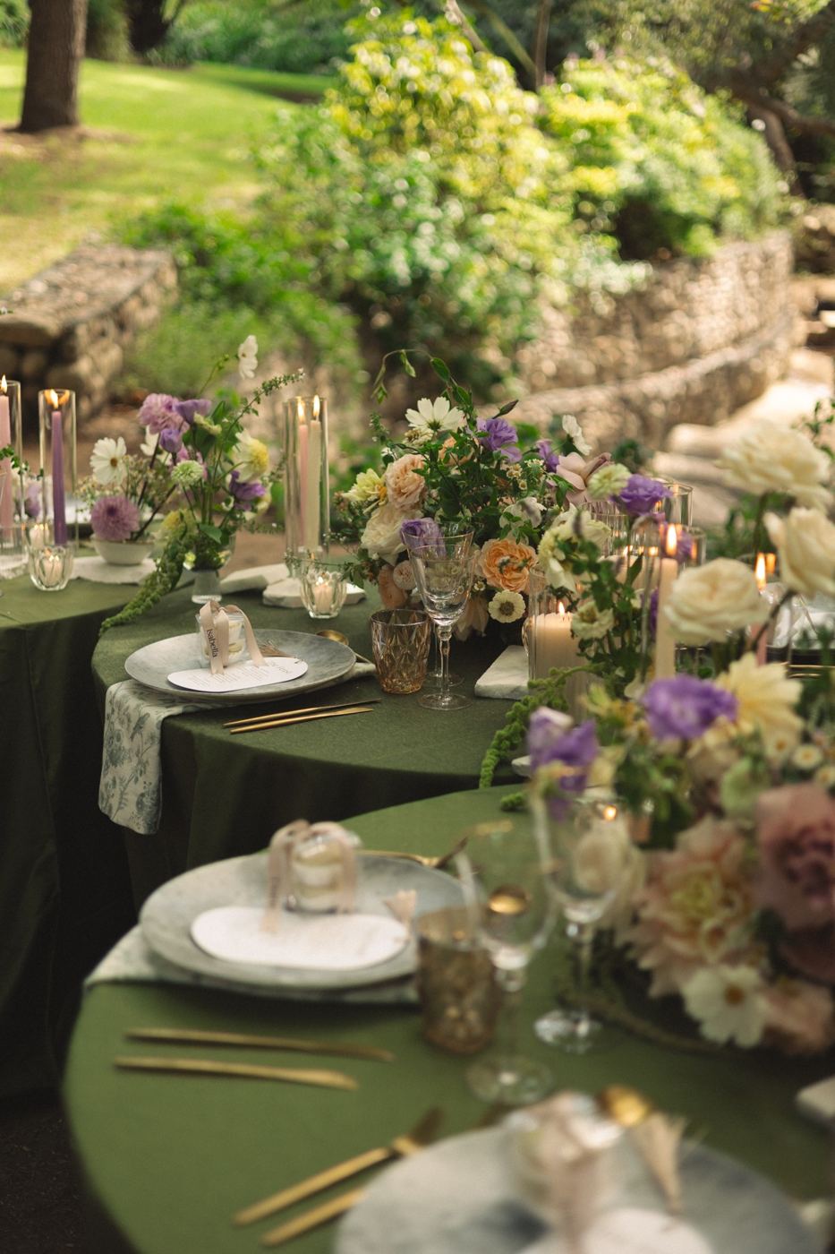 Styled event table with green cloth and florals in a garden