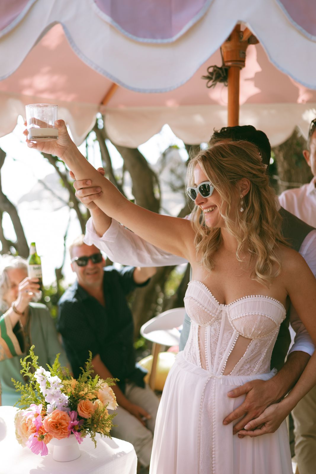 Bride raising a toast under a scalloped pink umbrella