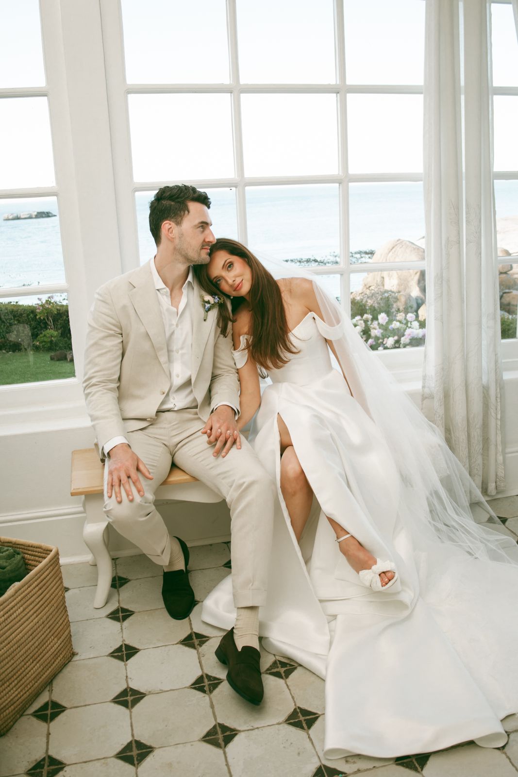 Couple seated by tall windows overlooking the ocean