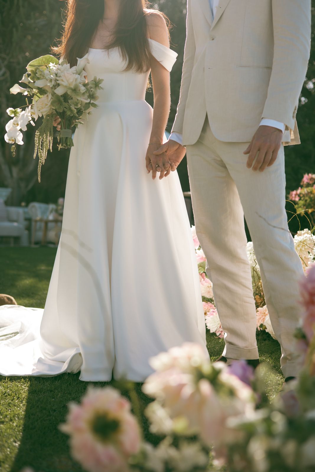 Couple holding hands among pink and white ceremony florals