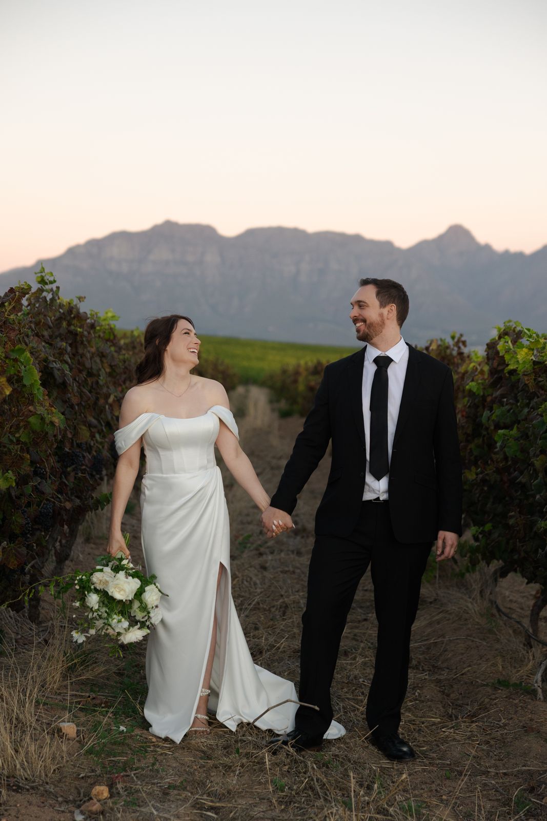 Couple walking hand in hand through the vineyards