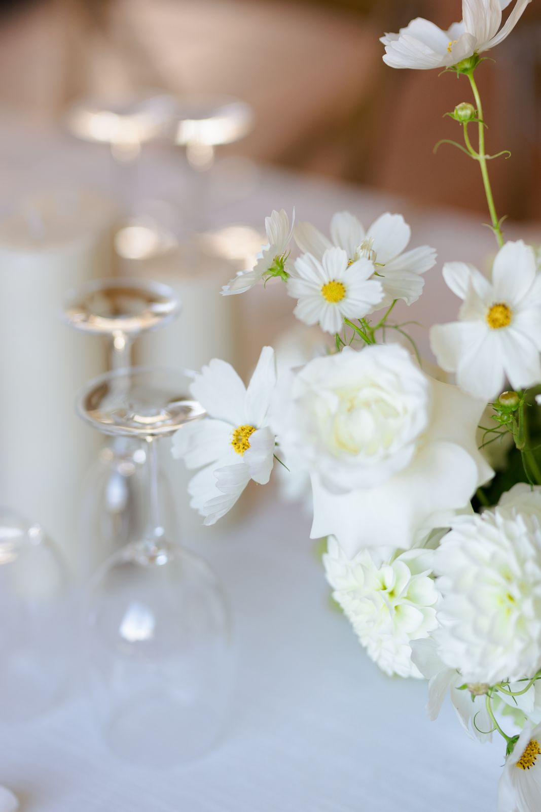 White cosmos and dahlias beside glassware