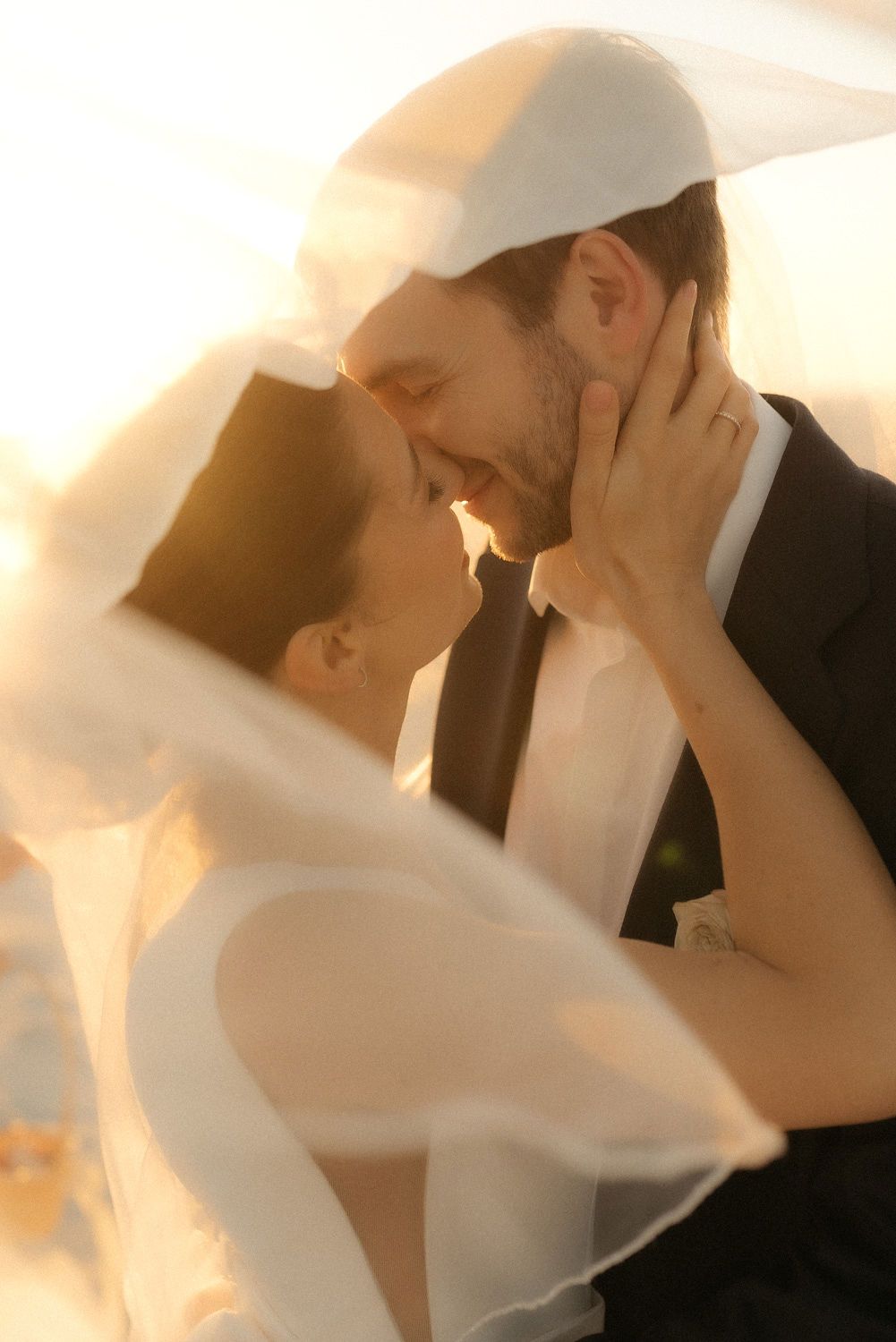 Couple kissing beneath a sunlit veil