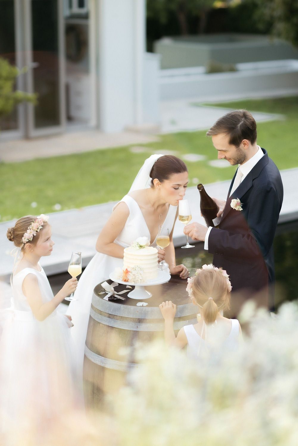 Couple sharing cake and champagne with flower girls