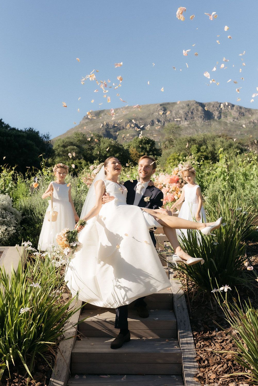 Groom carrying the bride through falling petals