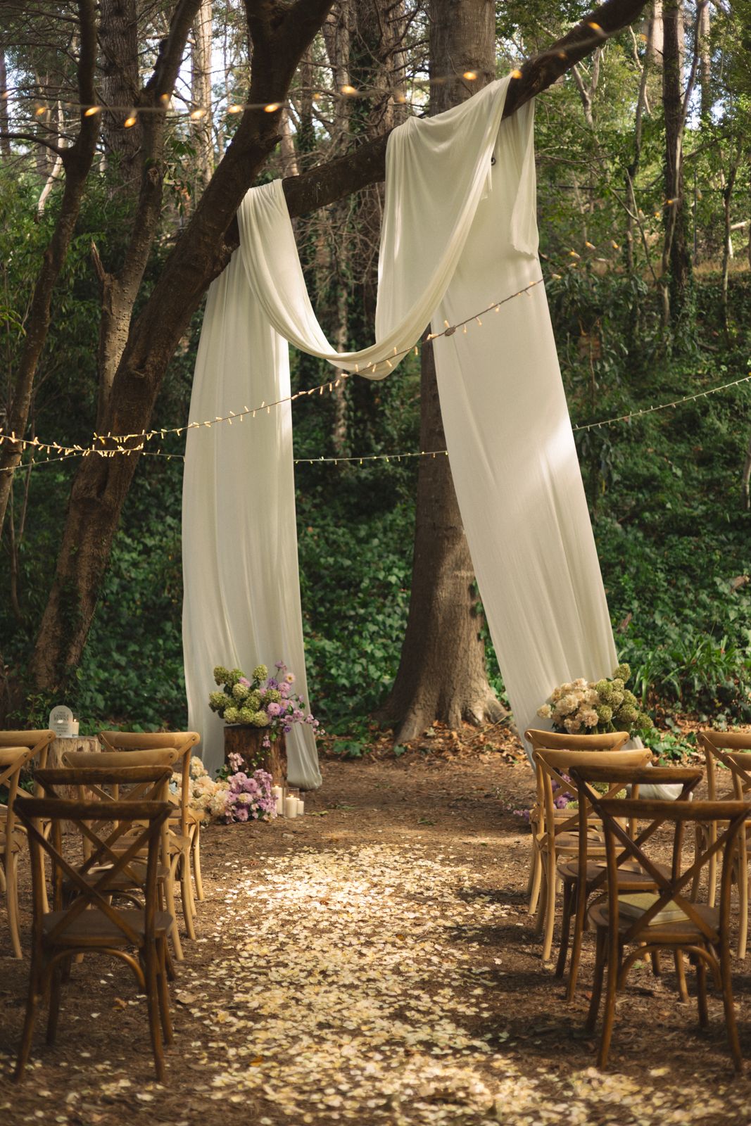 Forest ceremony aisle with draped white fabric between the trees
