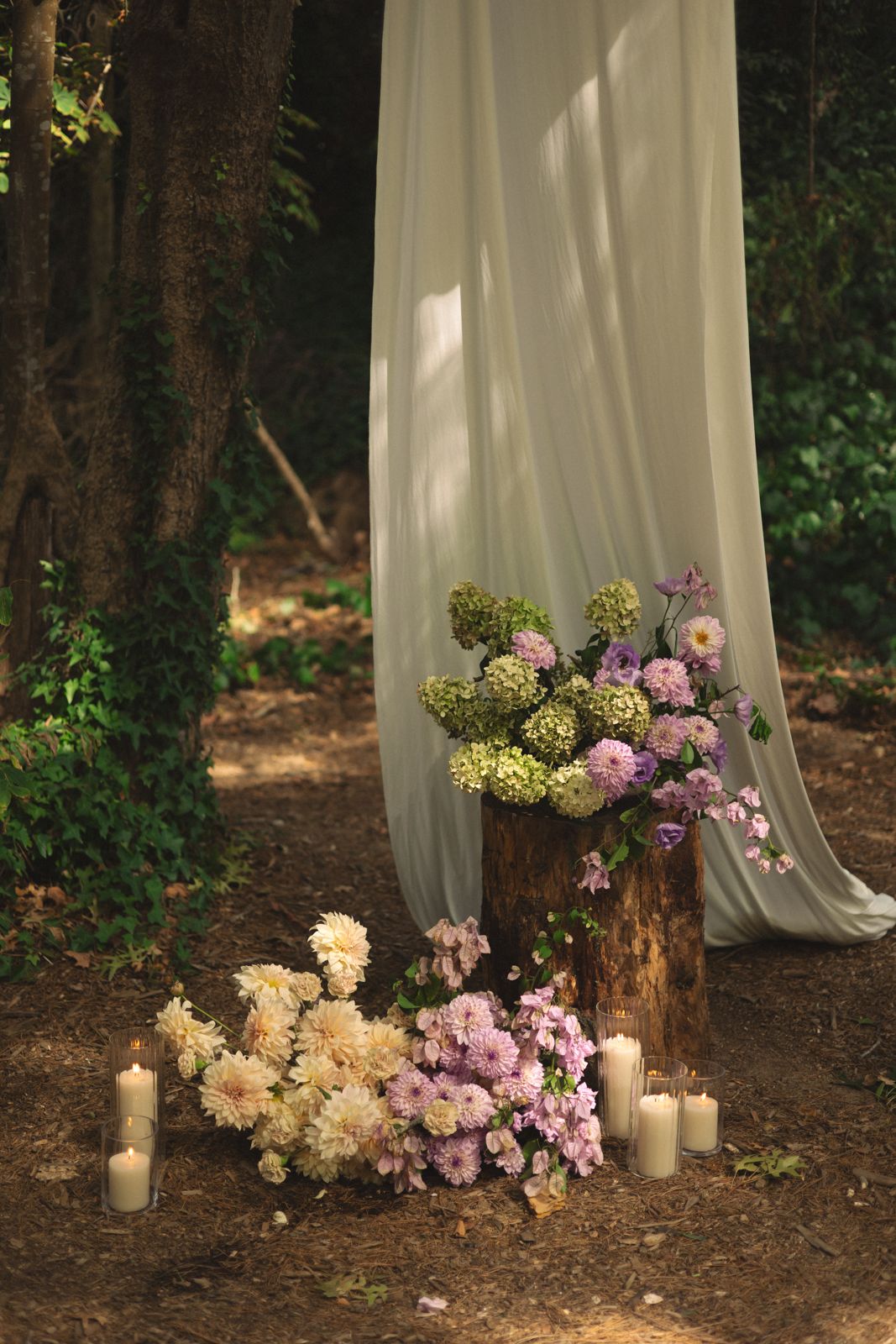 Draped fabric and florals at the base of a tree