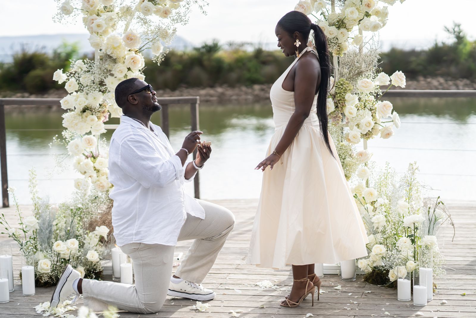 Proposal beneath a white floral arch on a jetty