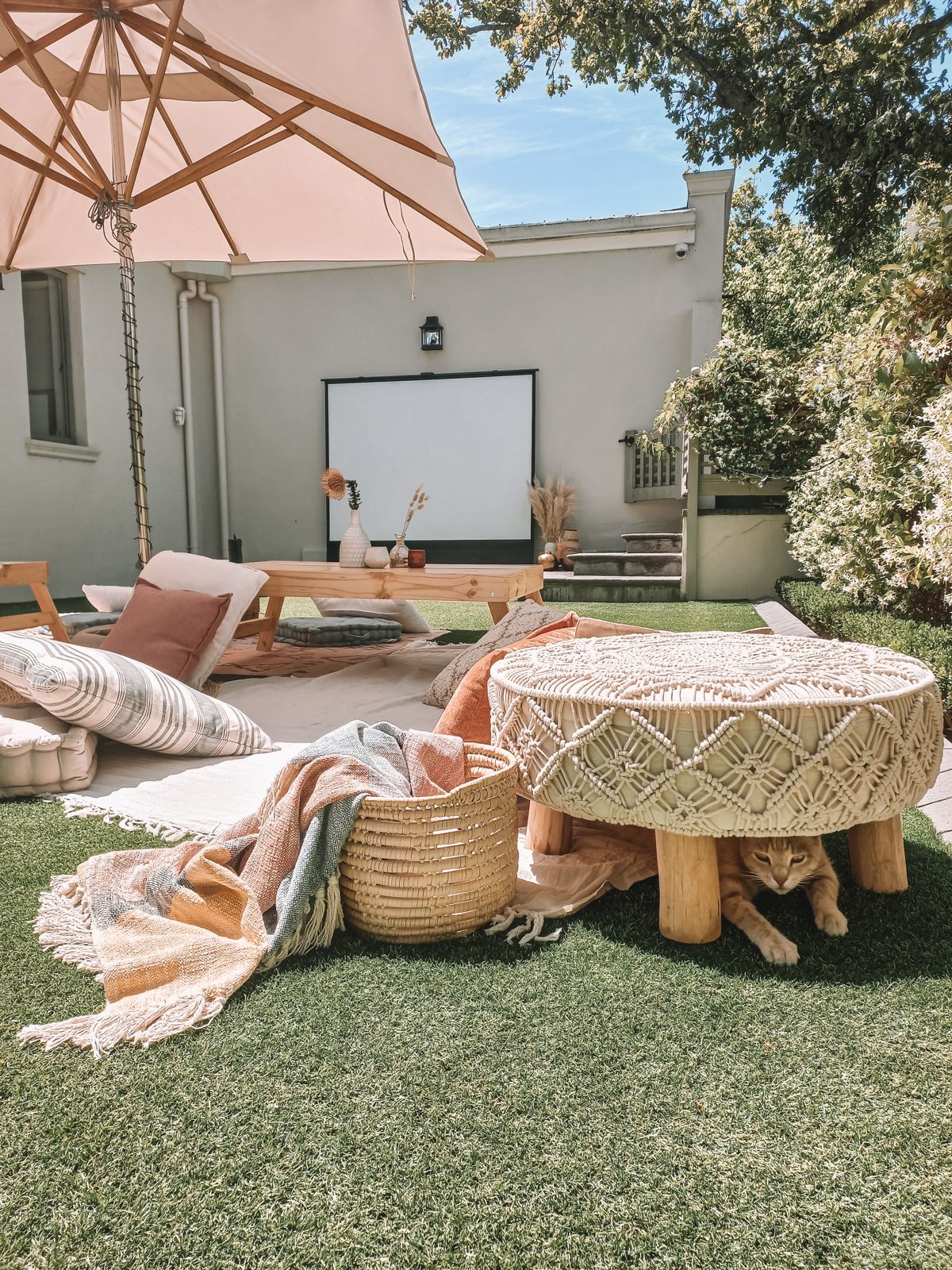 Garden cinema set-up with cushions and a parasol