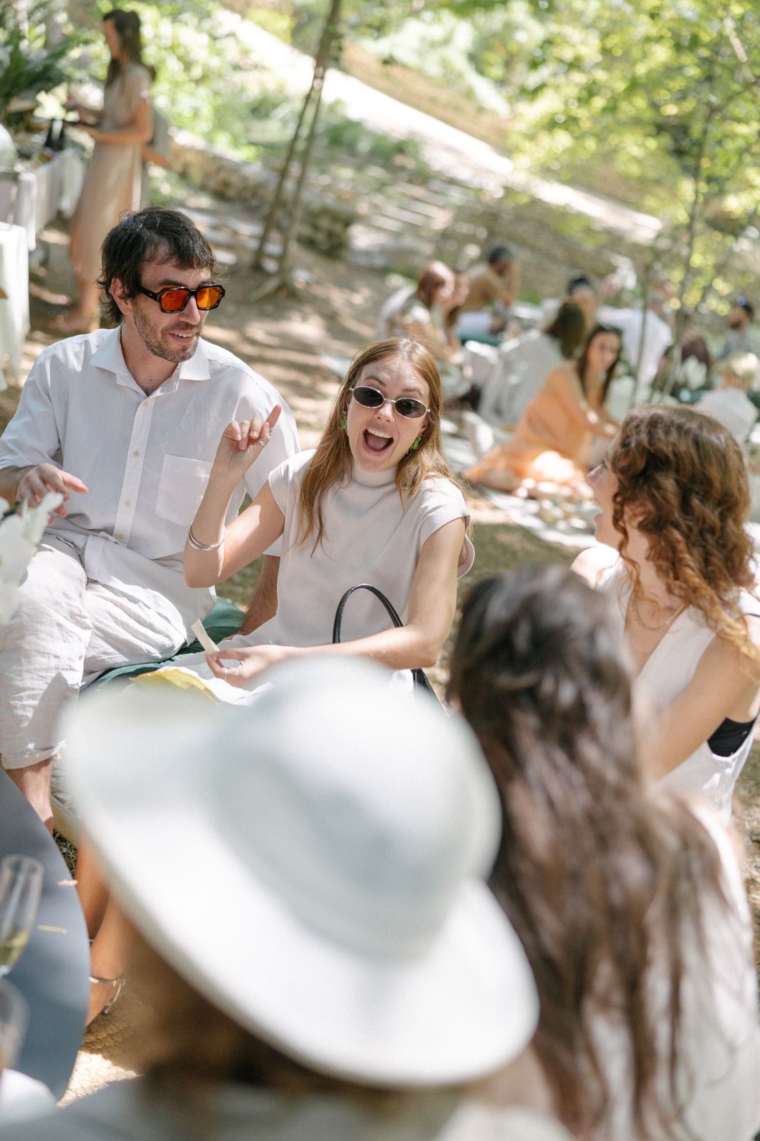 Guests laughing together on picnic cushions under the trees