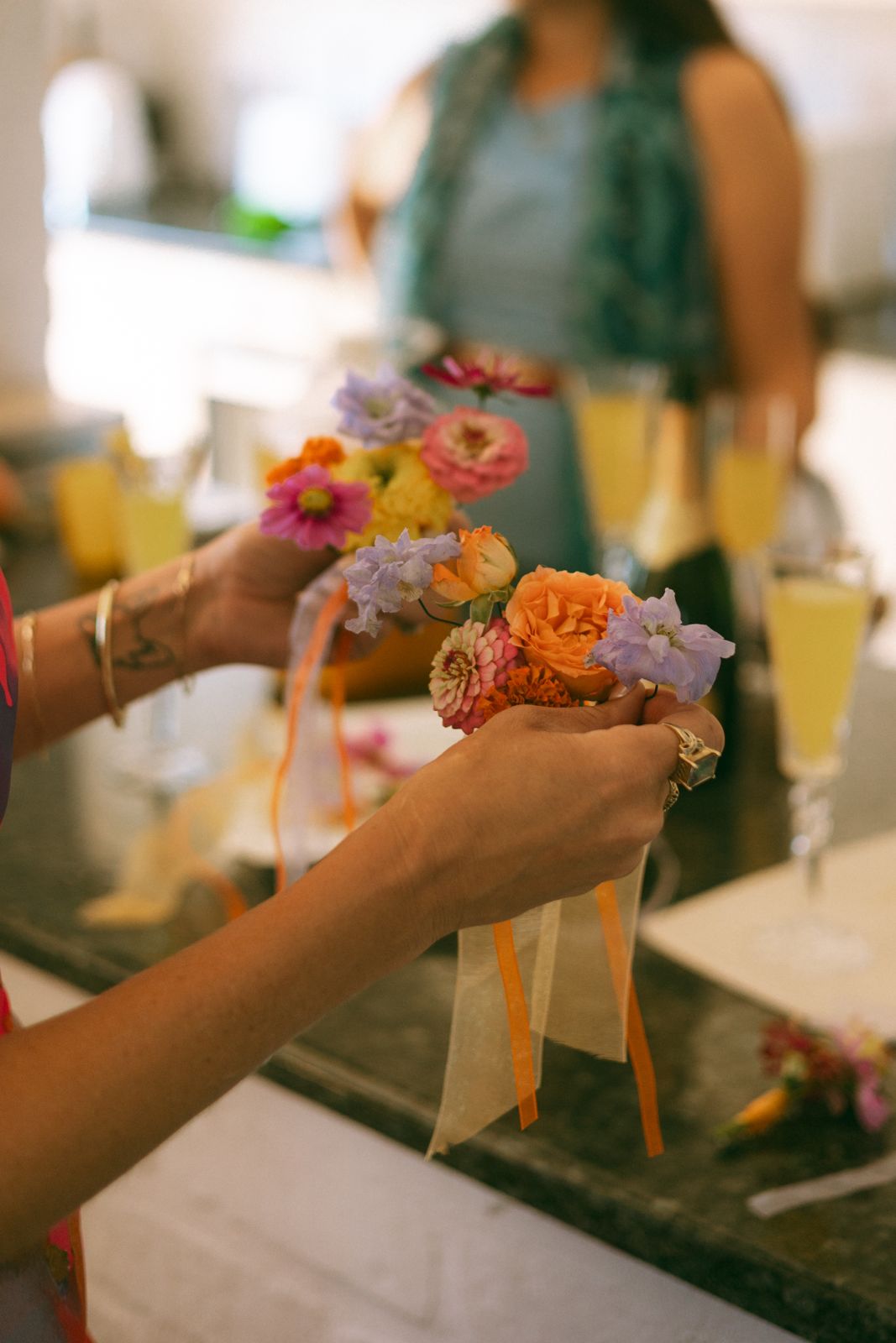 Hands tying bright buttonhole posies with ribbon