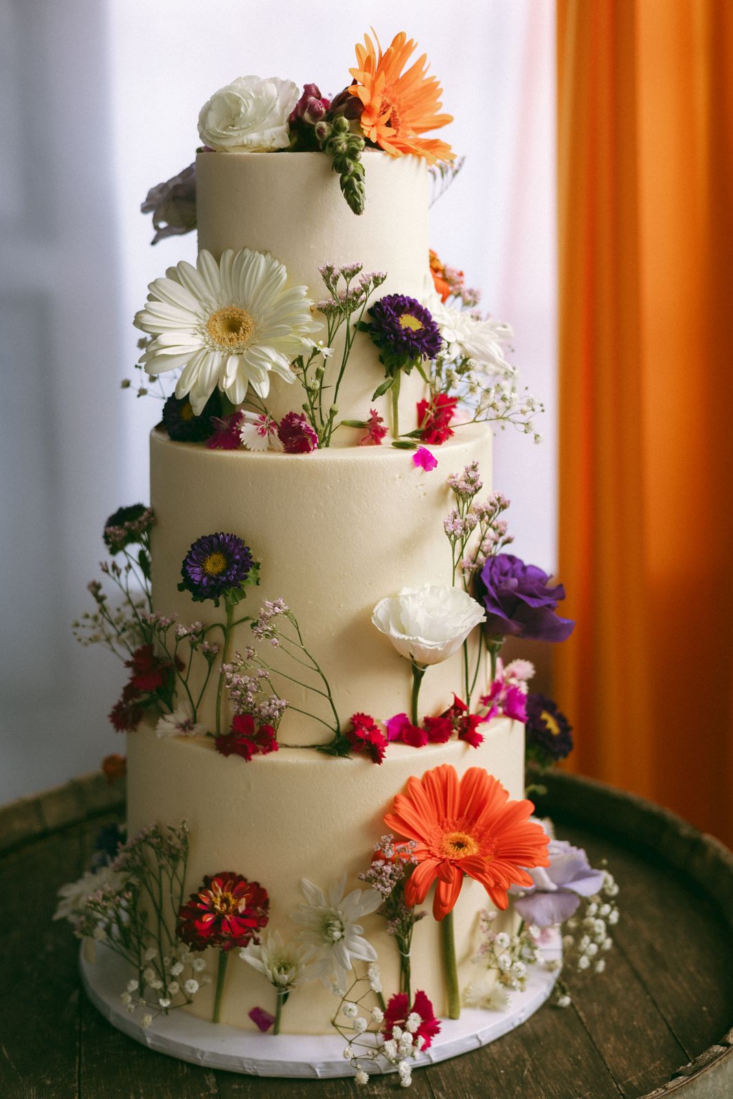 Three-tier buttercream cake dressed in fresh flowers