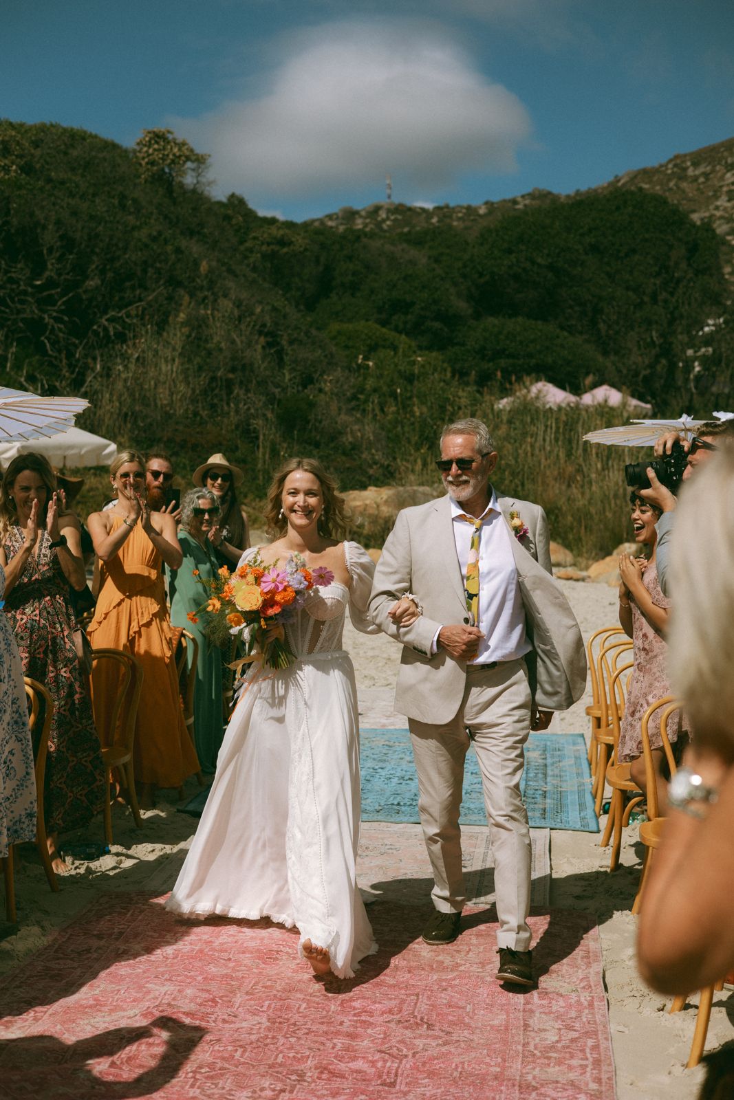 Bride walking down a rug-lined aisle on the beach