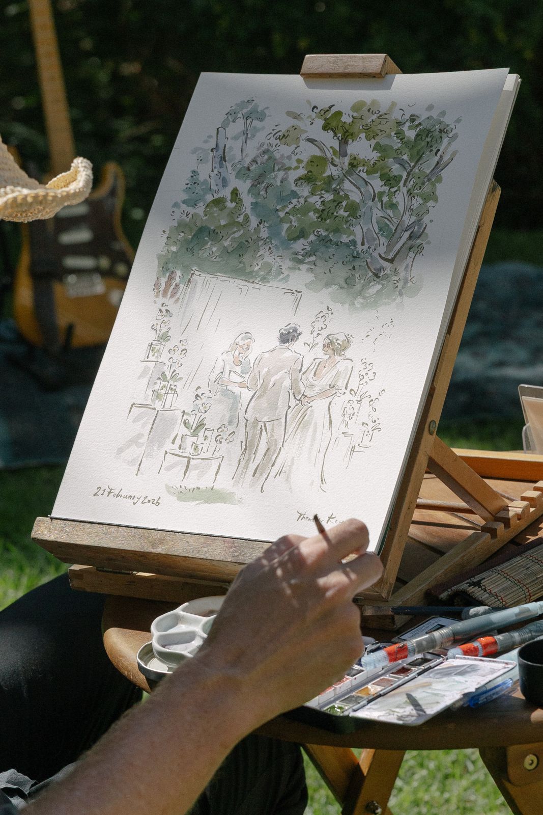 Live wedding painter at work on an easel in the garden
