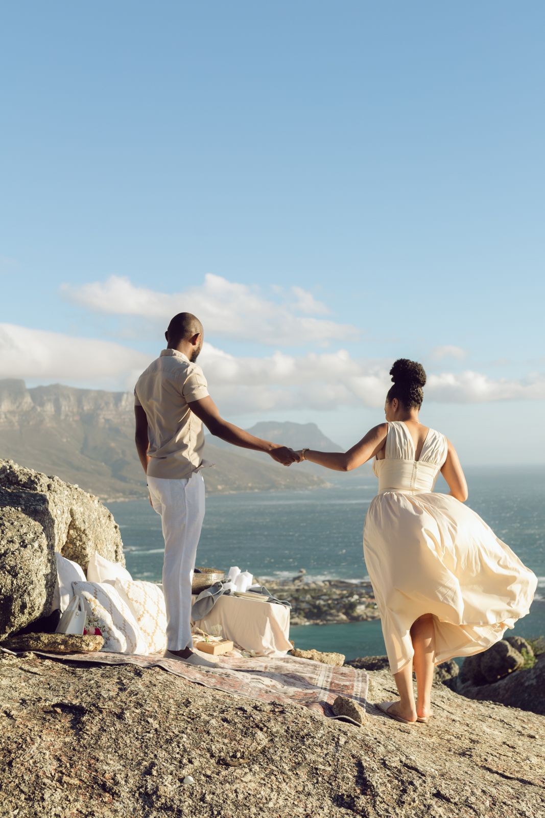 Couple holding hands on rocks above the sea