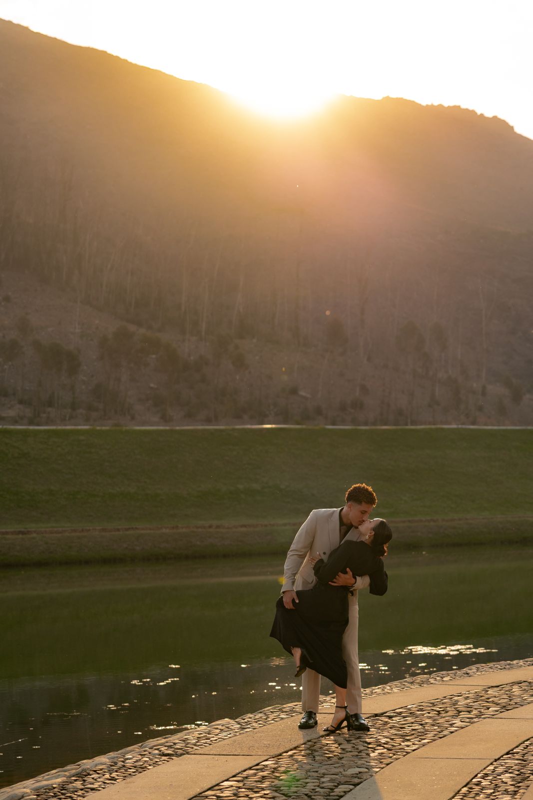 Couple dip kiss at sunset beside a lake