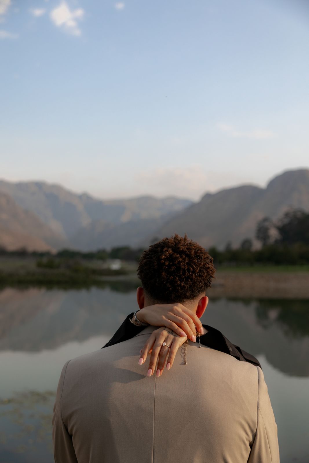 Hands with an engagement ring, looking over a lake