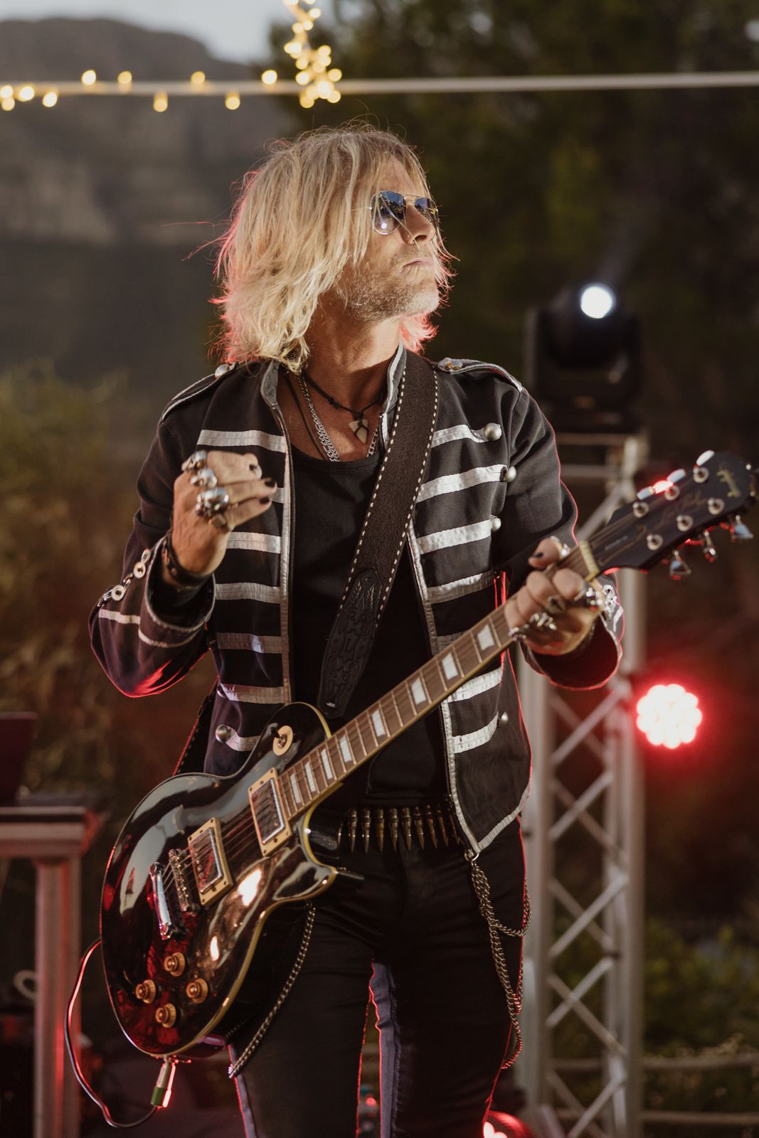 Guitarist performing on an outdoor stage at dusk