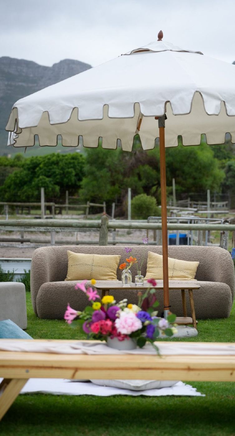 Outdoor lounge set-up under a white umbrella with mountains behind